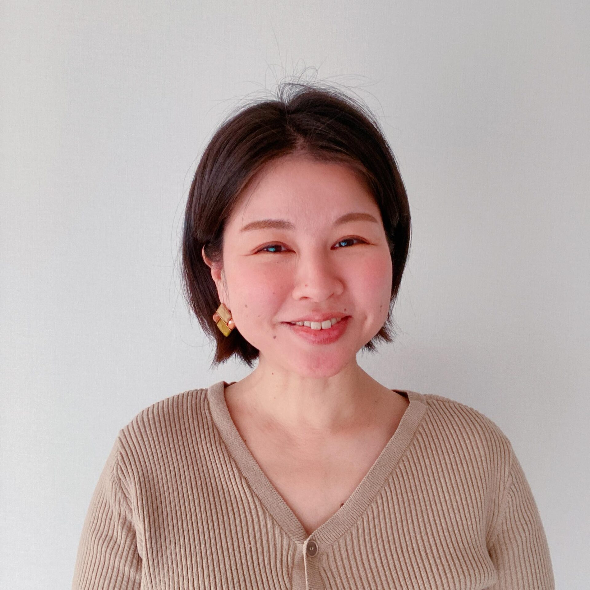 赤褐色のタートルネックと白いバッグを身に付けた女性の横顔。目を閉じて見上げている。